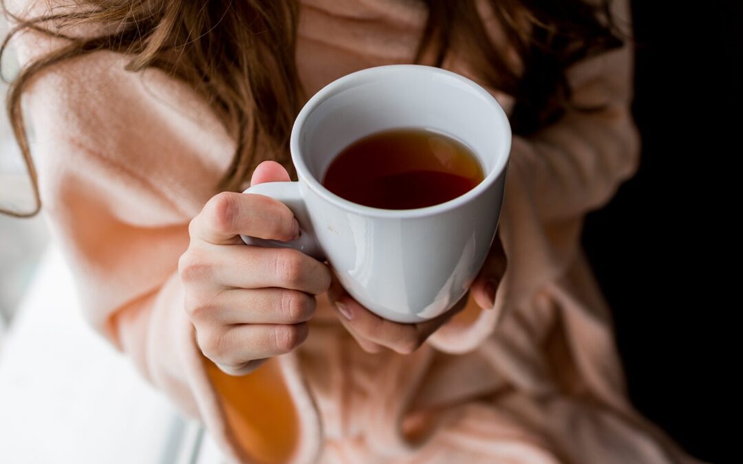 close-up of a woman in cozy loungewear holding a cup of tea
