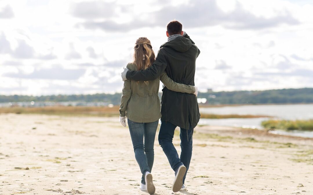 Couple walking arm in arm on a beach